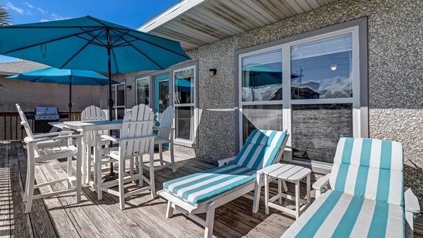 A deck with white furniture, including lounge chairs and a table, under a large blue umbrella. - Redecorated Pet Friendly Home by RedAwning (Fernandina Beach)