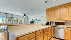 A modern kitchen with wooden cabinets, a stainless steel dishwasher, and a microwave. - Redecorated Pet Friendly Home by RedAwning (Fernandina Beach)