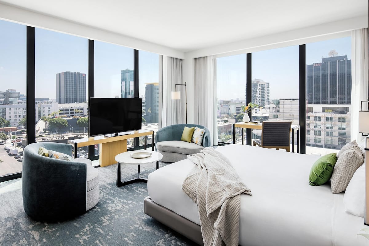 Une chambre d’hôtel moderne dotée d’un grand lit, d’une télévision, d’un bureau et d’une chaise, le tout offrant une vue sur la ville.