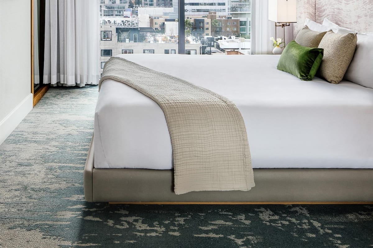 Une chambre d’hôtel moderne avec un grand lit, une vue sur la ville et un décor minimaliste.