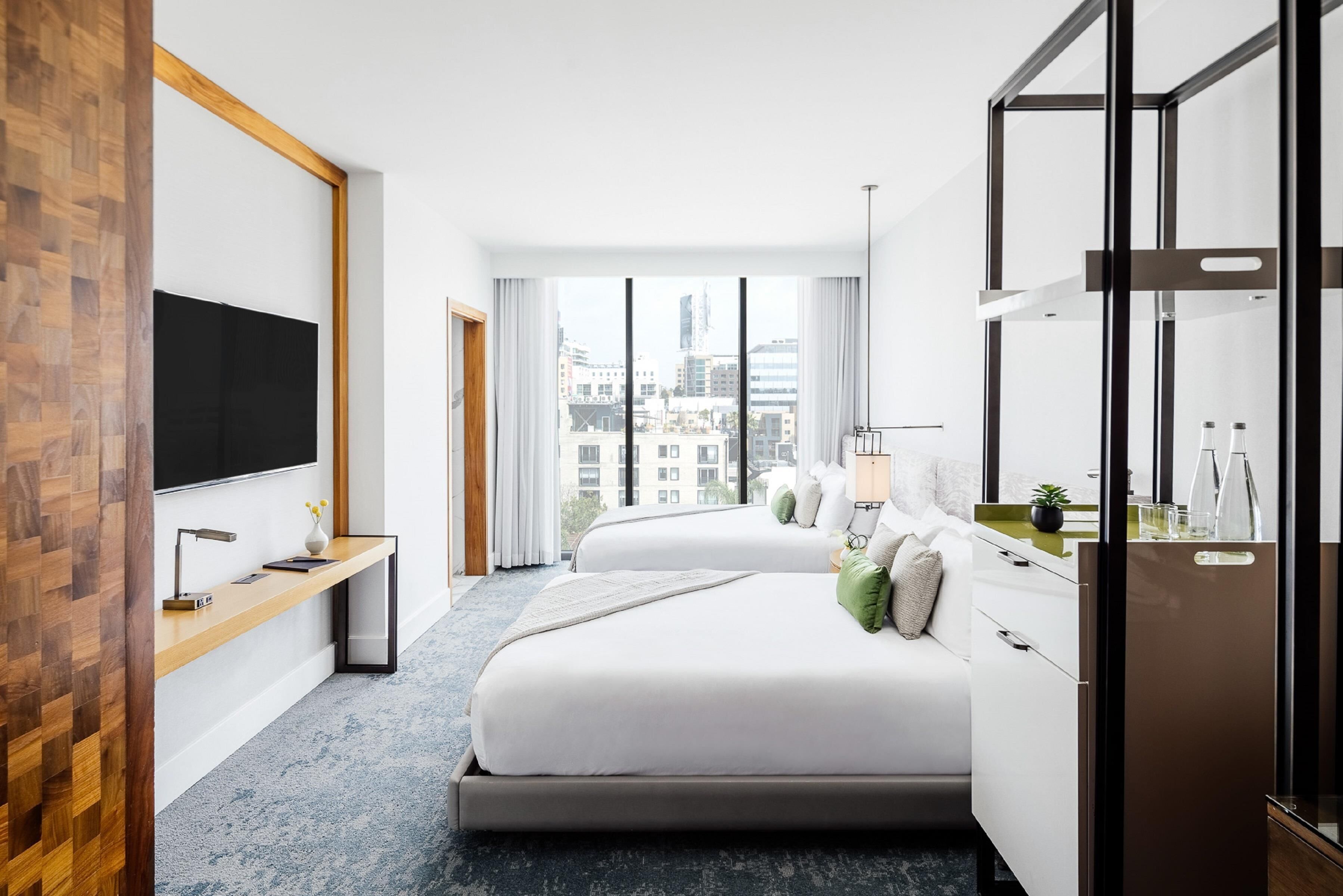 Een moderne hotelkamer met een groot bed, een televisie, een bureau en uitzicht op de stad.