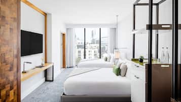 Moderni hotellihuone, jossa on suuri sänky, televisio, työpöytä ja näkymä kaupunkiin.