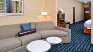 A hotel room with a sofa, two small tables, a lamp, a mirror, and a bed. - Fairfield Inn & Suites Sacramento Airport Woodland (Woodland)