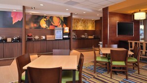 A hotel dining area with wooden tables and chairs, a coffee station, and a large mural on the wall. - Fairfield Inn & Suites Sacramento Airport Woodland (Woodland)