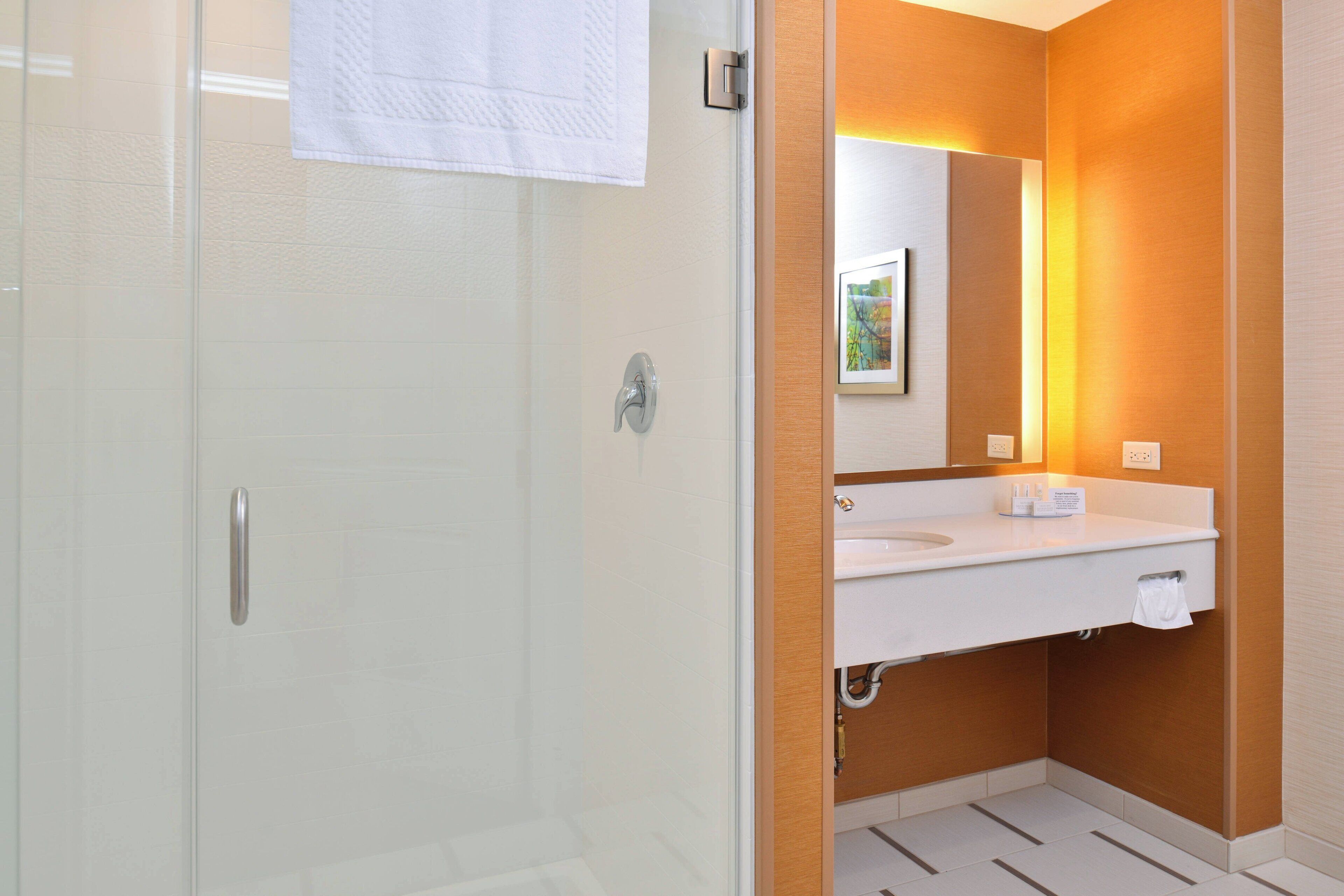 Une salle de bain moderne avec une porte de douche en verre, un lavabo blanc et un meuble-lavabo en bois.