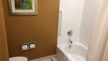 A bathroom with a toilet, a sink with a towel dispenser, and a bathtub with a shower curtain.
