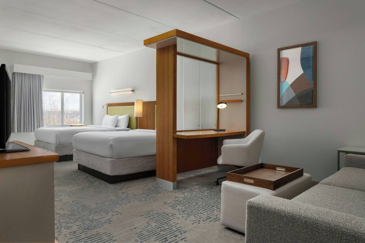 A hotel room with a bed, two bedside tables, a desk, a chair, and a large mirror.