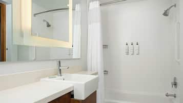 Une salle de bain moderne avec un meuble-lavabo à deux vasques, un grand miroir, une douche avec une porte en verre et des articles de toilette fixés au mur.