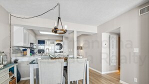 A modern kitchen with white cabinets, a central island, and a hanging light fixture.