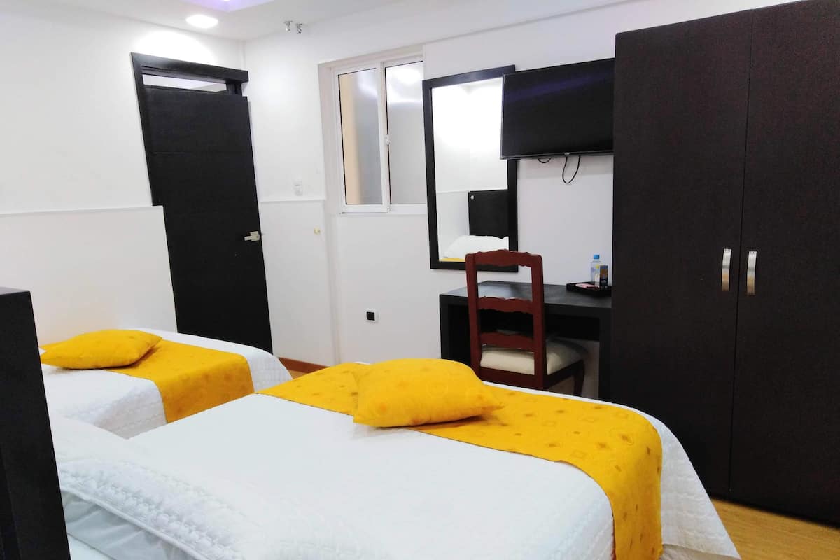 A room with two beds, a desk, a chair, and a wardrobe.