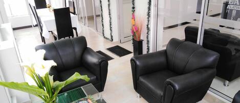 A modern hotel lobby with leather sofas, a glass coffee table, and a decorative plant.