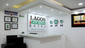 A reception desk with a sign for the Lagos Latin America Hotel, featuring framed certificates and a glass display case. - Hotel Lagos Latin America (San Juan de Pasto)