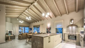 A spacious kitchen with a large island, wooden ceiling beams, and a modern stove.