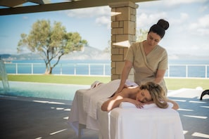 A massage therapy session in a spa with a view of the sea and mountains.