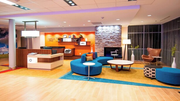 A modern lobby with a reception desk, seating areas, a fireplace, and a stone accent wall. - Fairfield Inn & Suites San Antonio Brooks City Base (San Antonio)