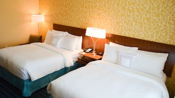 Une chambre d’hôtel avec deux lits, une table de chevet avec une lampe et un mur décoré d’un motif.