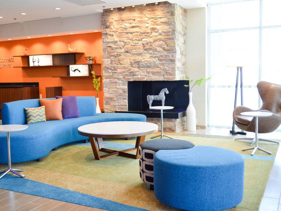Un área de descanso moderna con una pared de piedra, asientos azules y una chimenea.