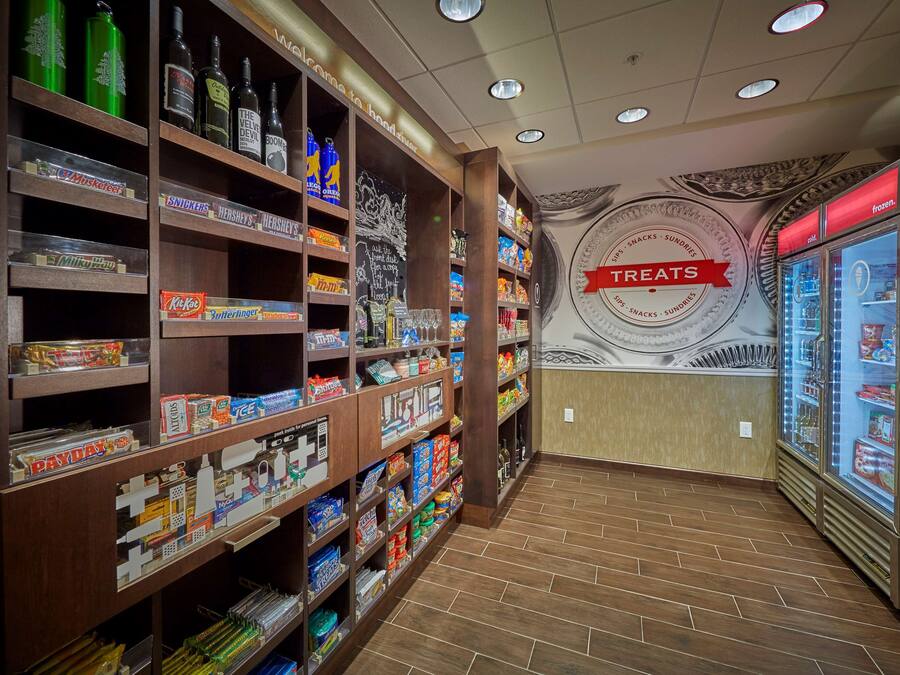 A snack and beverage section with shelves stocked with various products, a wall mural, and a refrigerated display case.