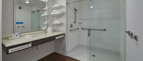 Een moderne badkamer met een douchecabine van glas, een grote spiegel en een wastafelmeubel met een wastafel en handdoekrekken.
