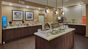 A buffet setup with a self-service station, a waffle maker, and various food containers.