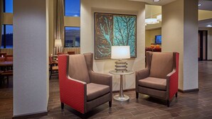 A lobby with two armchairs, a table, and a painting. - Hampton Inn & Suites Hood River (Hood River)