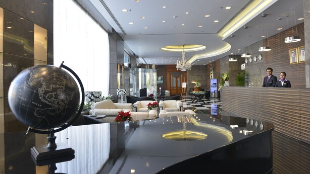 A modern lobby with a reception desk, seating area, and a globe. - Asdal Boutique Hotel Seef (Manama)