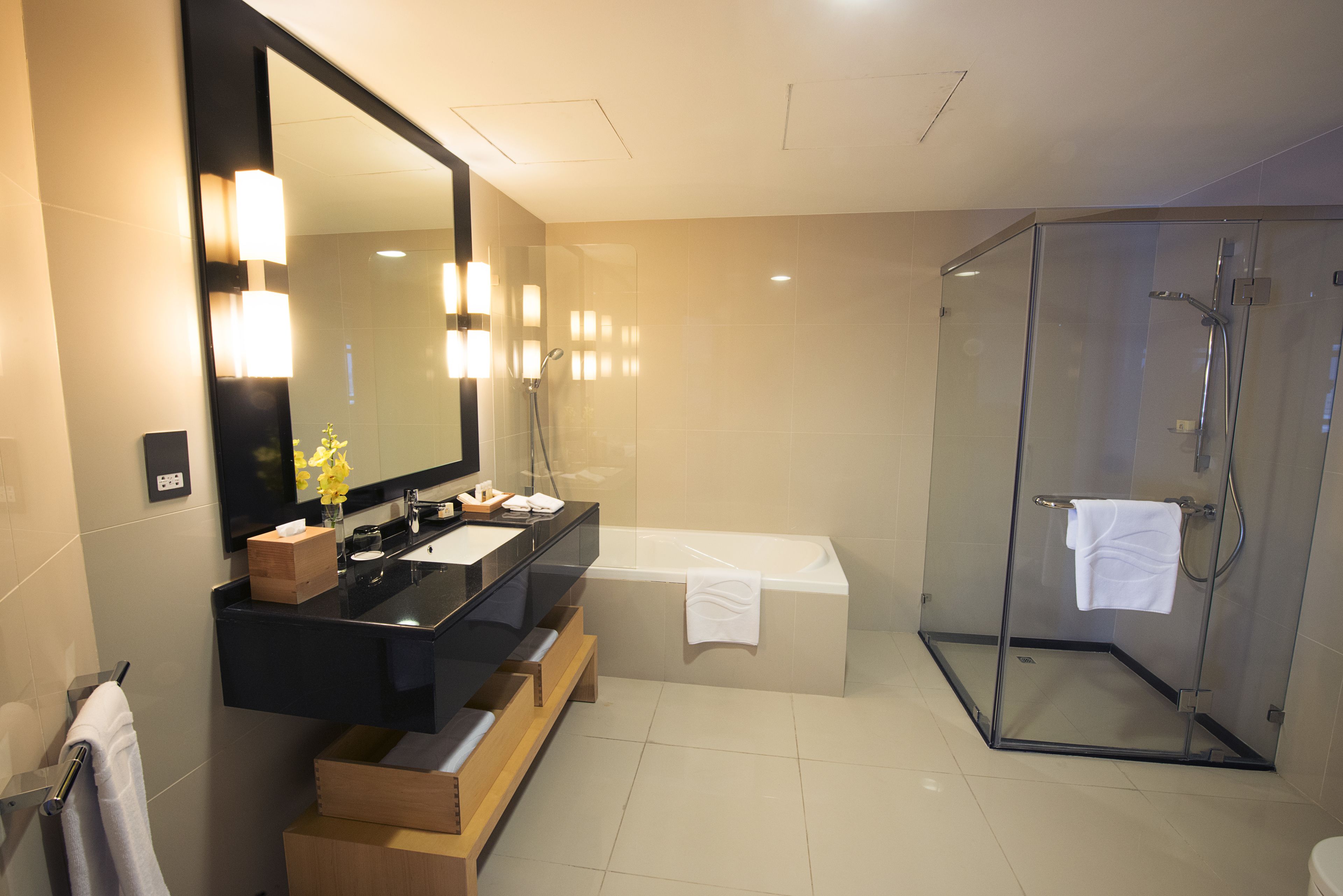 A modern bathroom with a glass-enclosed shower, a large mirror, and a black vanity with a sink.