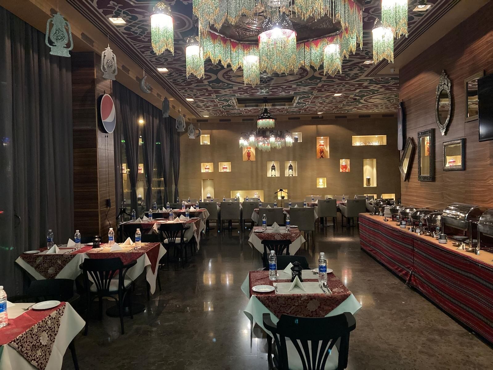 A restaurant with multiple tables, chairs, and a buffet area.