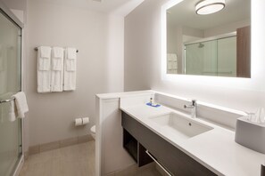 A modern bathroom with a glass shower enclosure, a white sink with a mirror above it, and a towel rack with multiple towels. - Holiday Inn Express & Suites Blackwell by IHG (Blackwell)