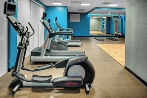A gym with multiple treadmills, a mirrored wall, and exercise balls.