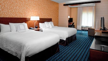 A hotel room with two beds, a desk, a TV, and a bathroom.