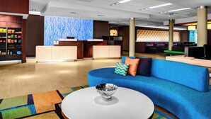 Een moderne lobby met een receptiebalie, een zithoek en een decoratieve wand.