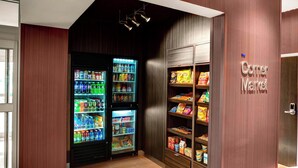 Een buurtwinkel met drankautomaten en planken vol snacks en levensmiddelen.