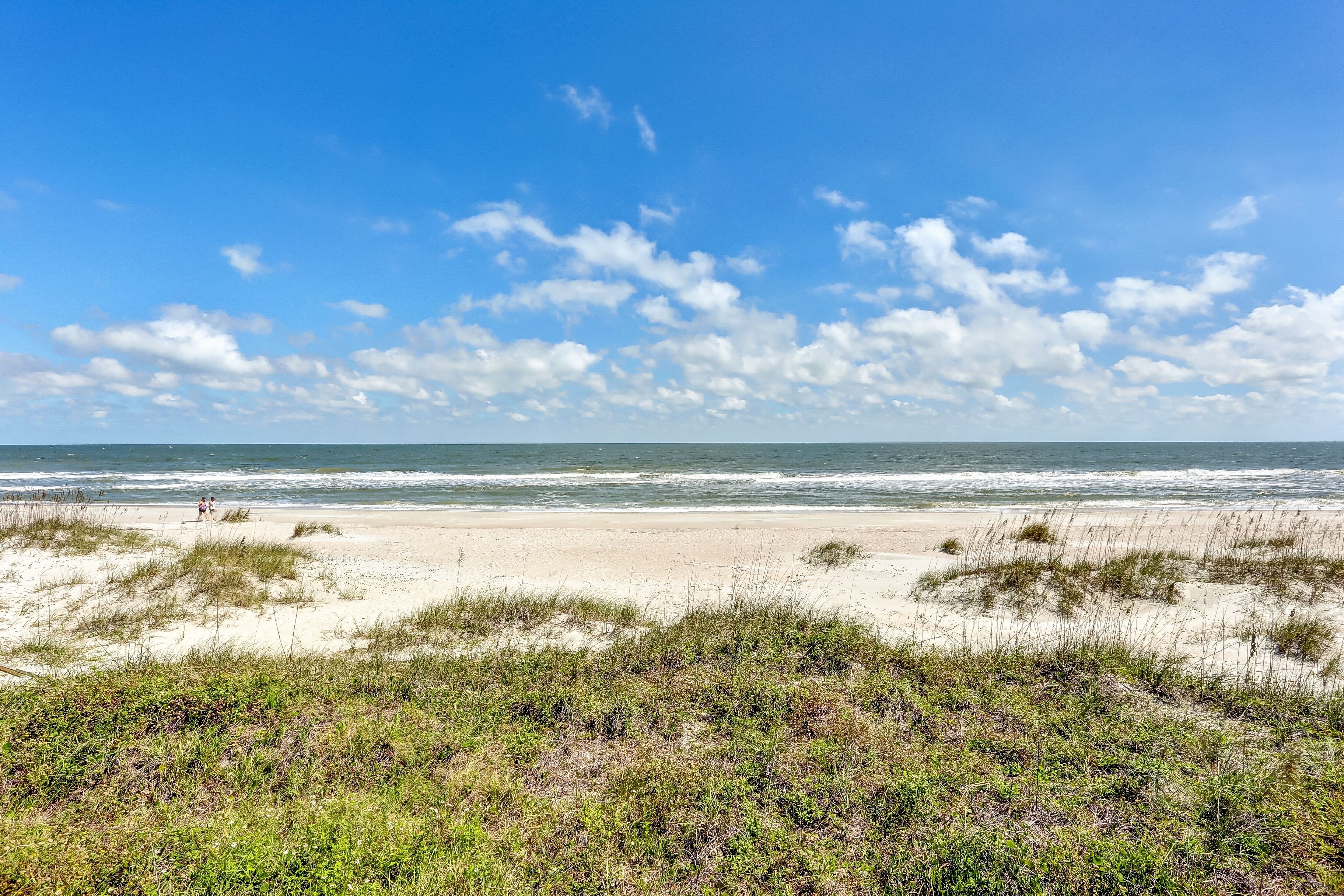 A beach with sand dunes and ocean waves.