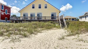 A yellow house with a wooden deck and a staircase leading to a second level. - 812 S. Fletcher - 3 Br Cottage (Fernandina Beach)
