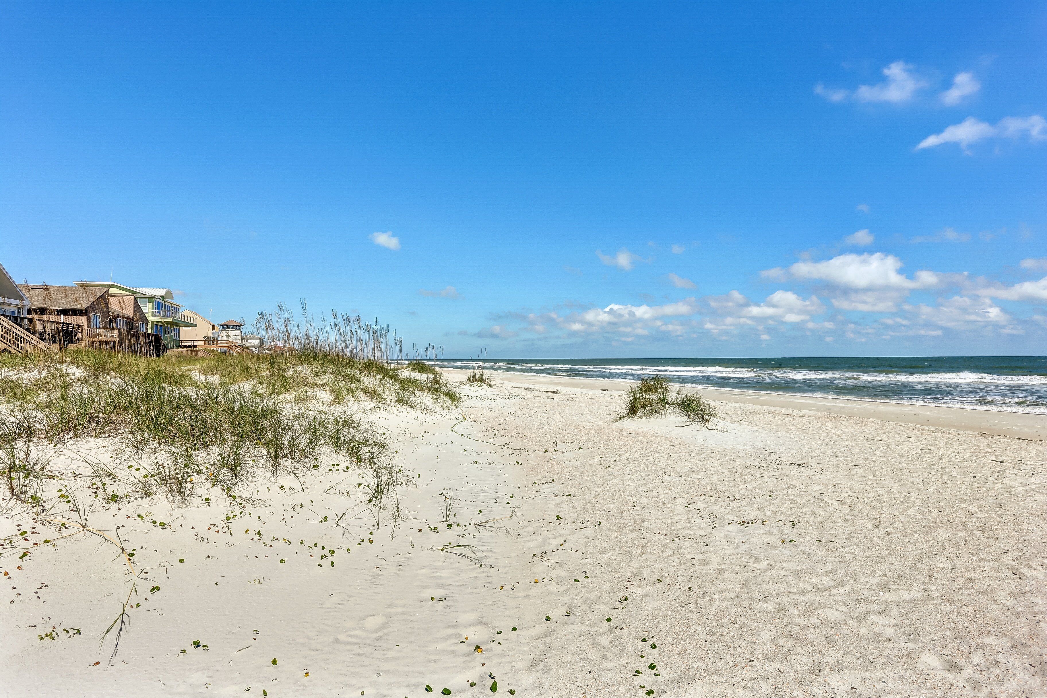 Une plage avec un rivage sablonneux et un bâtiment doté d’un toit de chaume.