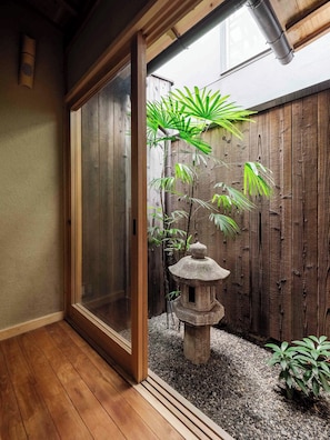 Un plancher en bois, une lanterne en pierre et une clôture en bois ornée de plantes.