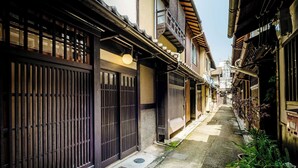 Un estrecho callejón con edificios japoneses tradicionales, puertas de madera y plantas en macetas.