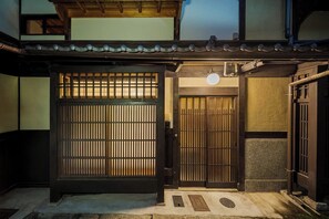 Une porte japonaise traditionnelle dotée d’une porte coulissante, d’un toit recouvert de tuiles et d’un petit espace en forme de porche.