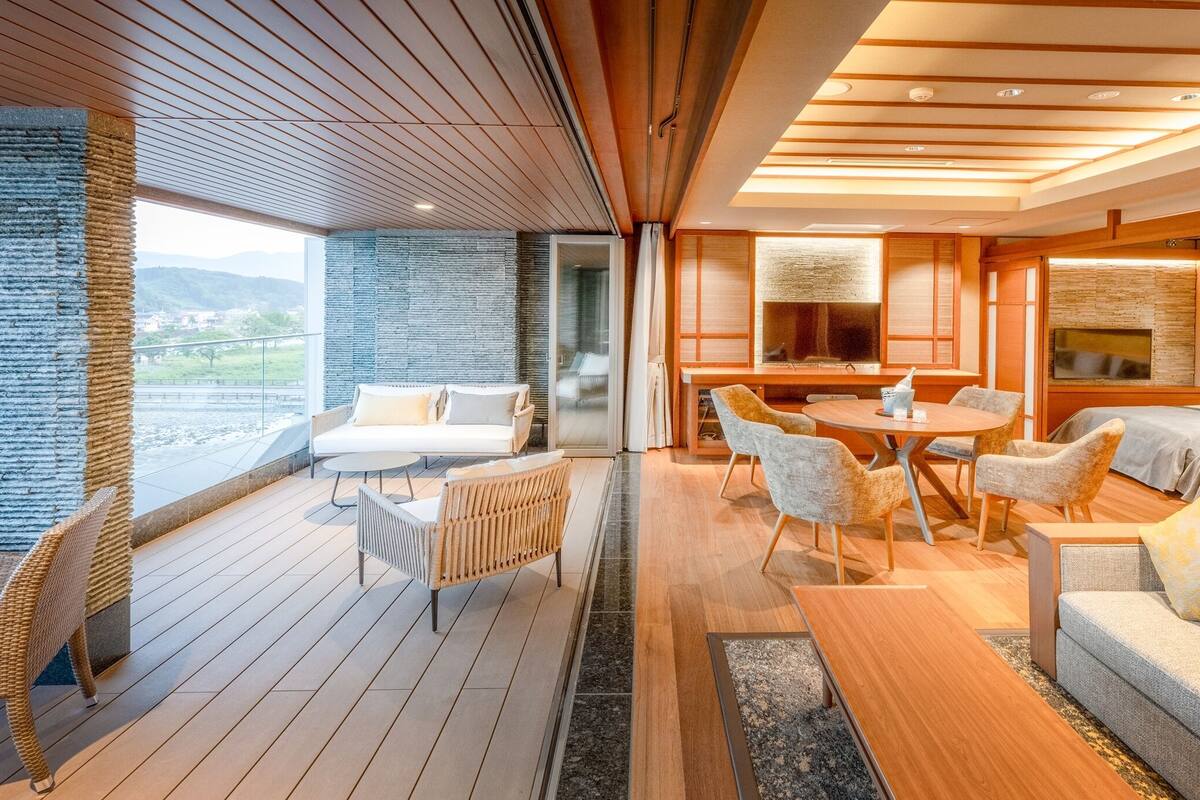 Een modern interieur met een houten terras, een eethoek en een slaapkamer met een groot raam.