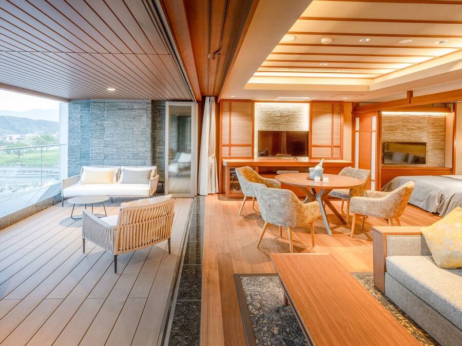 A modern interior with a wooden deck, a dining area, and a bedroom with a large window.