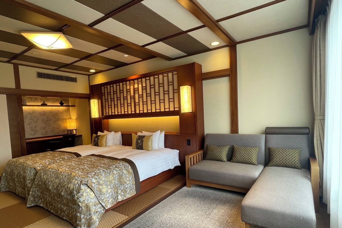 Een hotelkamer met een groot bed, een bank en een decoratief wandpaneel.