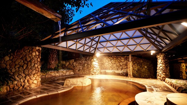 An outdoor hot tub area with stone walls and a wooden pergola overhead. - The Hamilton Ureshino (Ureshino)