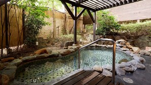 A hot spring area with a wooden deck, stone rocks, and a bamboo fence. - The Hamilton Ureshino (Ureshino)
