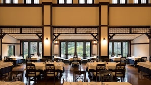 A large dining hall with multiple tables set for dining, high ceilings with wooden beams, and large windows providing natural light. - The Hamilton Ureshino (Ureshino)