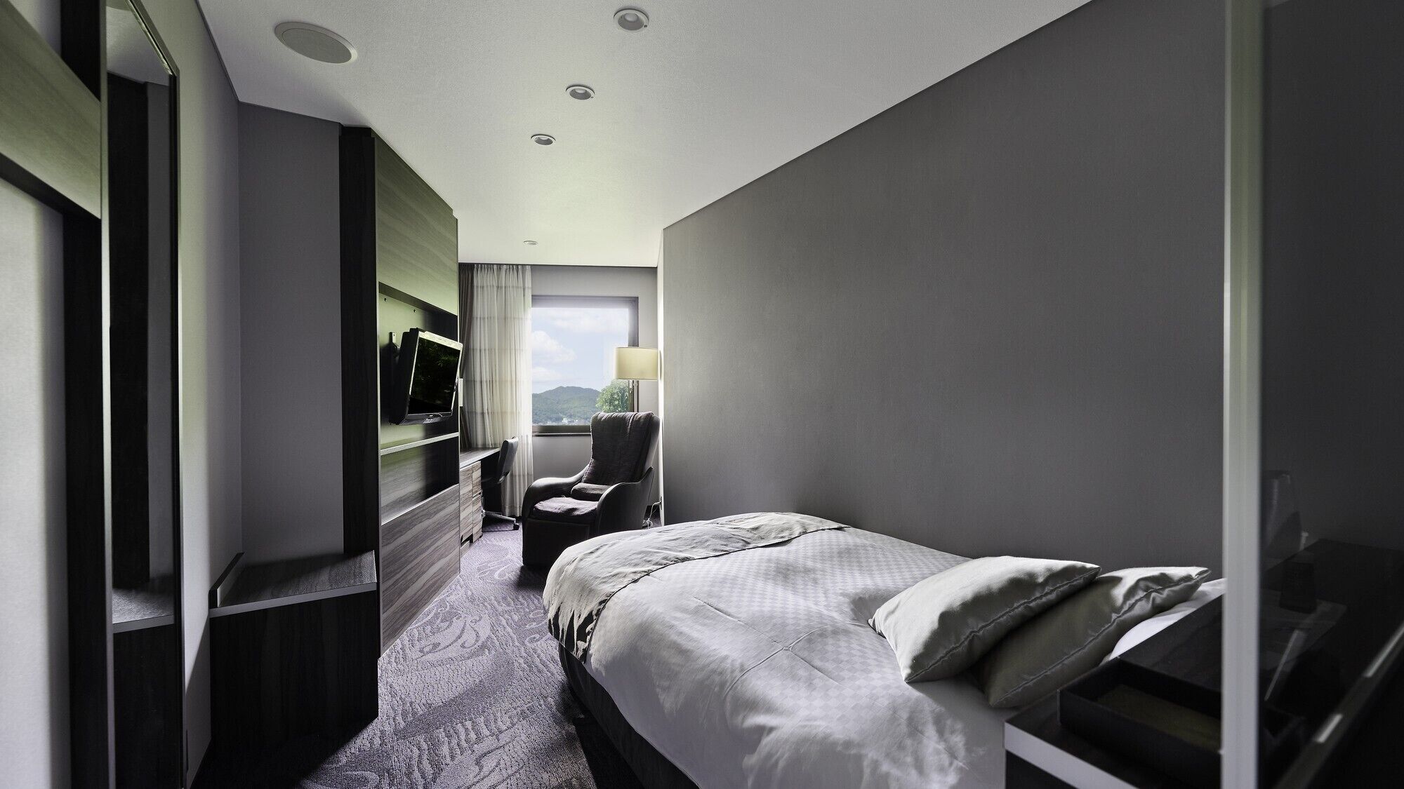 Une chambre d’hôtel avec un lit, une chaise, une télévision et un bureau.
