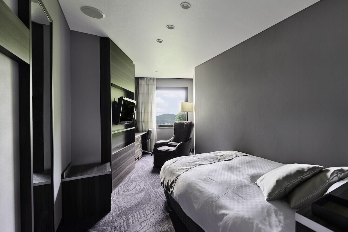 Une chambre d’hôtel avec un lit, une chaise, une télévision et un bureau.