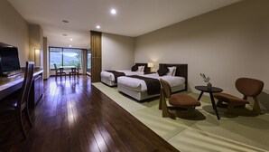 A hotel room with two beds, a desk, a TV, and a dining area with a view of the mountains. - NAGARAGAWA SEIRYU HOTEL (Gifu)