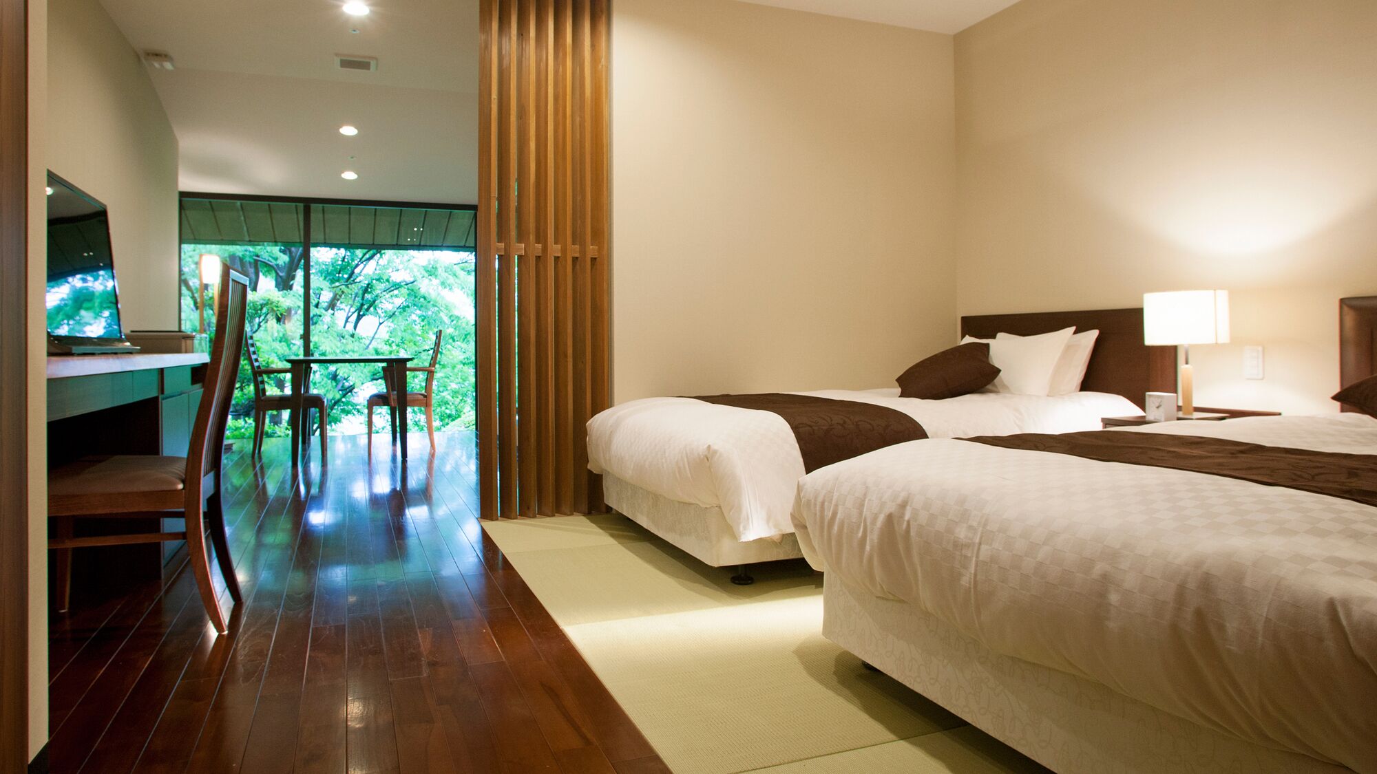 Une chambre d’hôtel avec deux lits, un bureau avec une chaise et une vue sur la verdure.