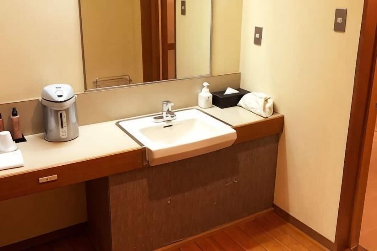 A hotel bathroom with a sink, mirror, towel, and a coffee maker.